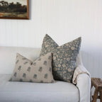 Light gray sofa with patterned pillows against a white wall.