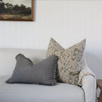 Gray and patterned pillows on a beige sofa with a neutral background, lifestyle