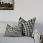 Light gray sofa with patterned cushions against a white wall.