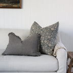 Decorative pillows on a sofa with a floral pattern and checkered design in a living room setting.