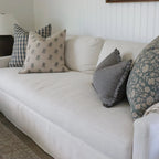 White sofa with patterned cushions in a room with a lamp and rug.