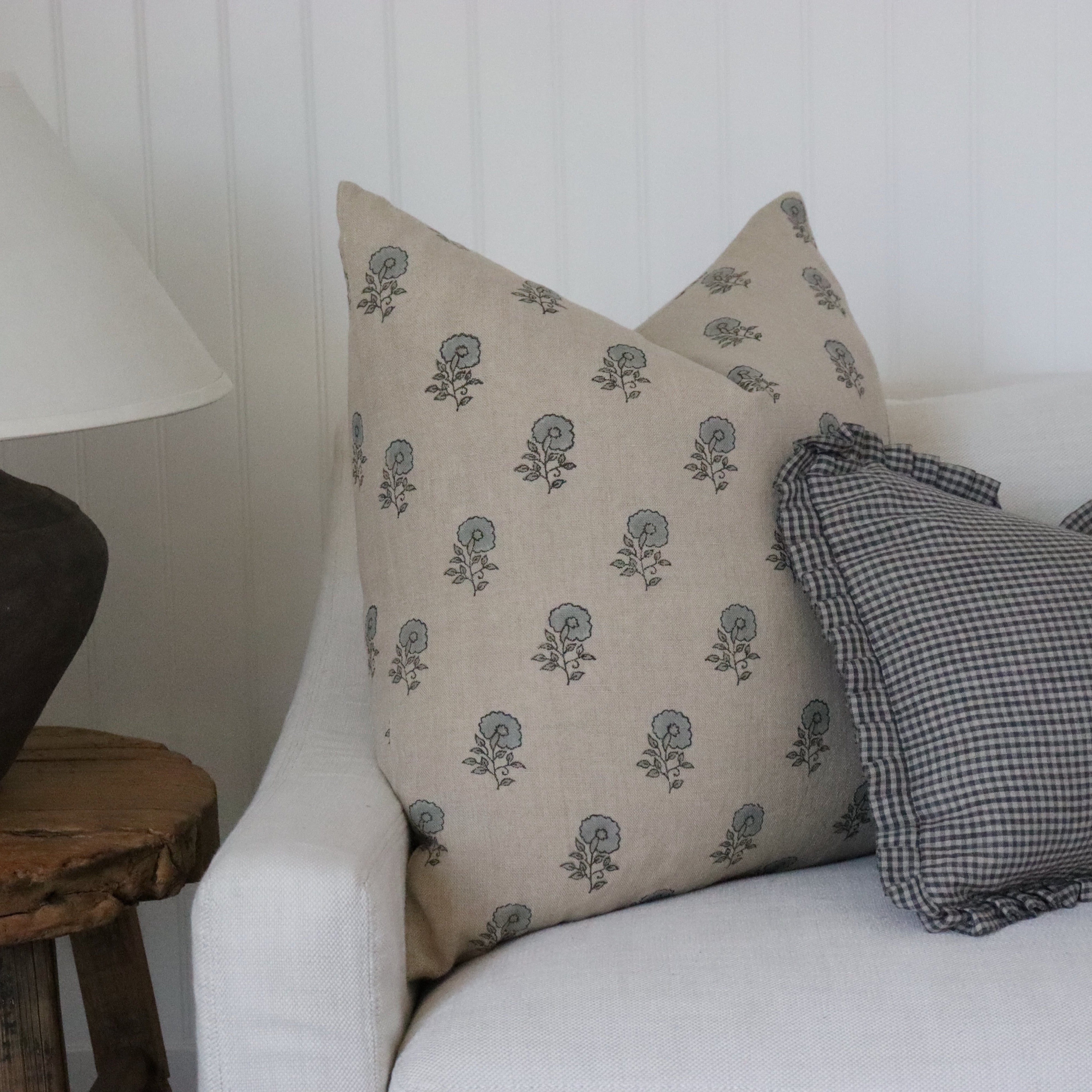 Decorative pillows on a white sofa with a lamp and wooden side table in the background.
