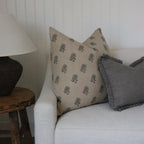 Gray sofa with patterned cushions and a wooden side table with a lamp.