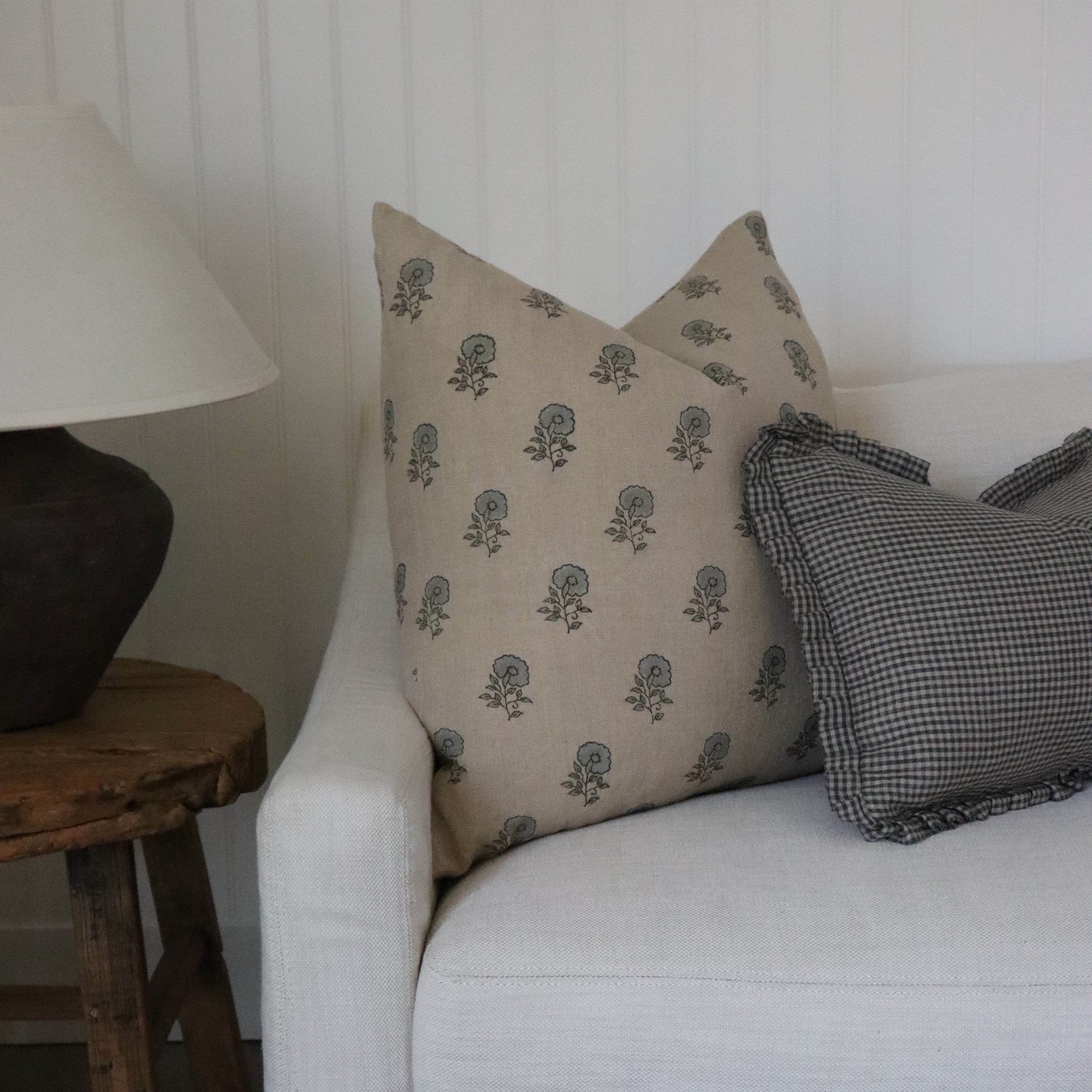 Gray sofa with patterned cushions and a wooden side table with a lamp.